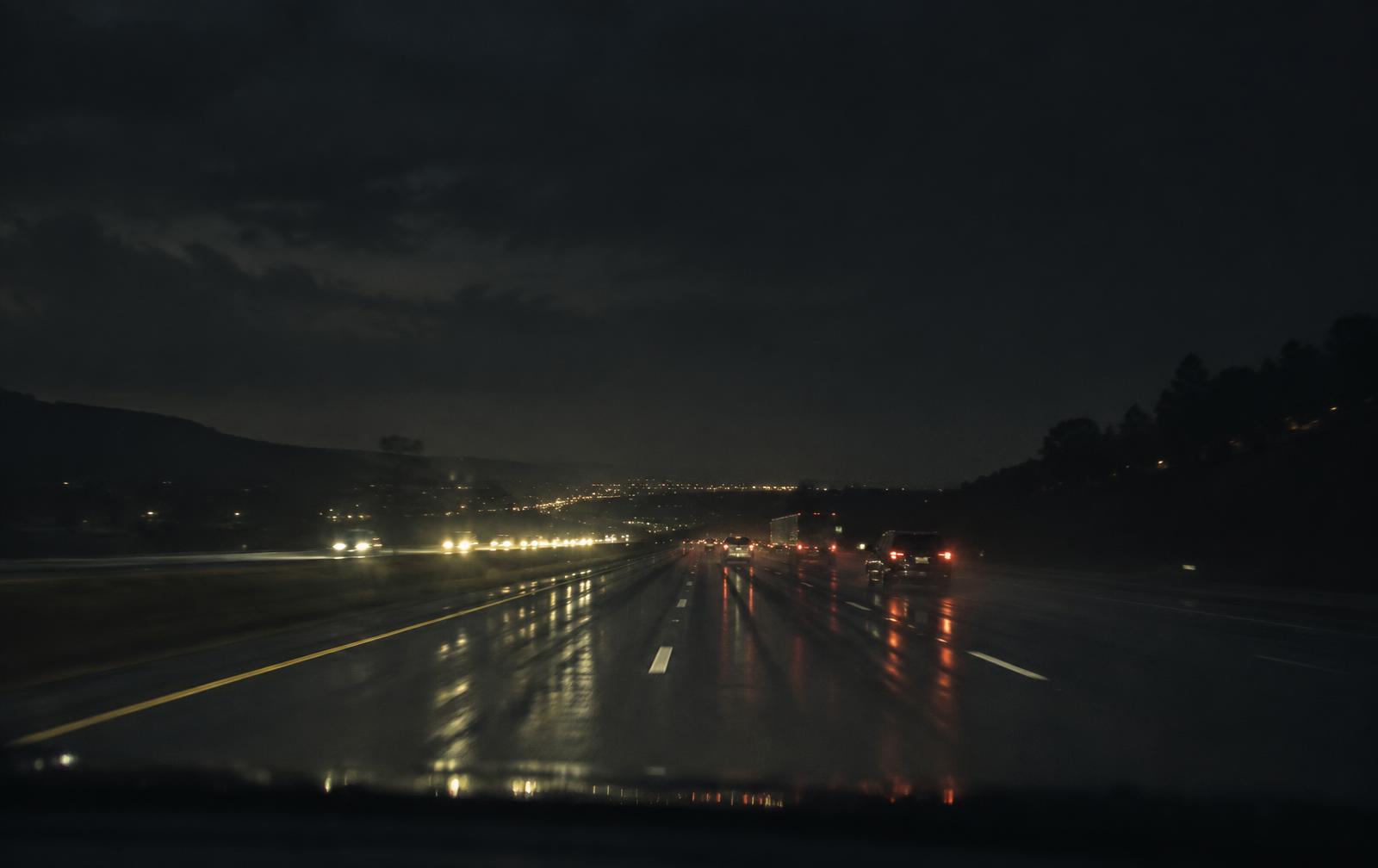 A rain-darkened highway at night